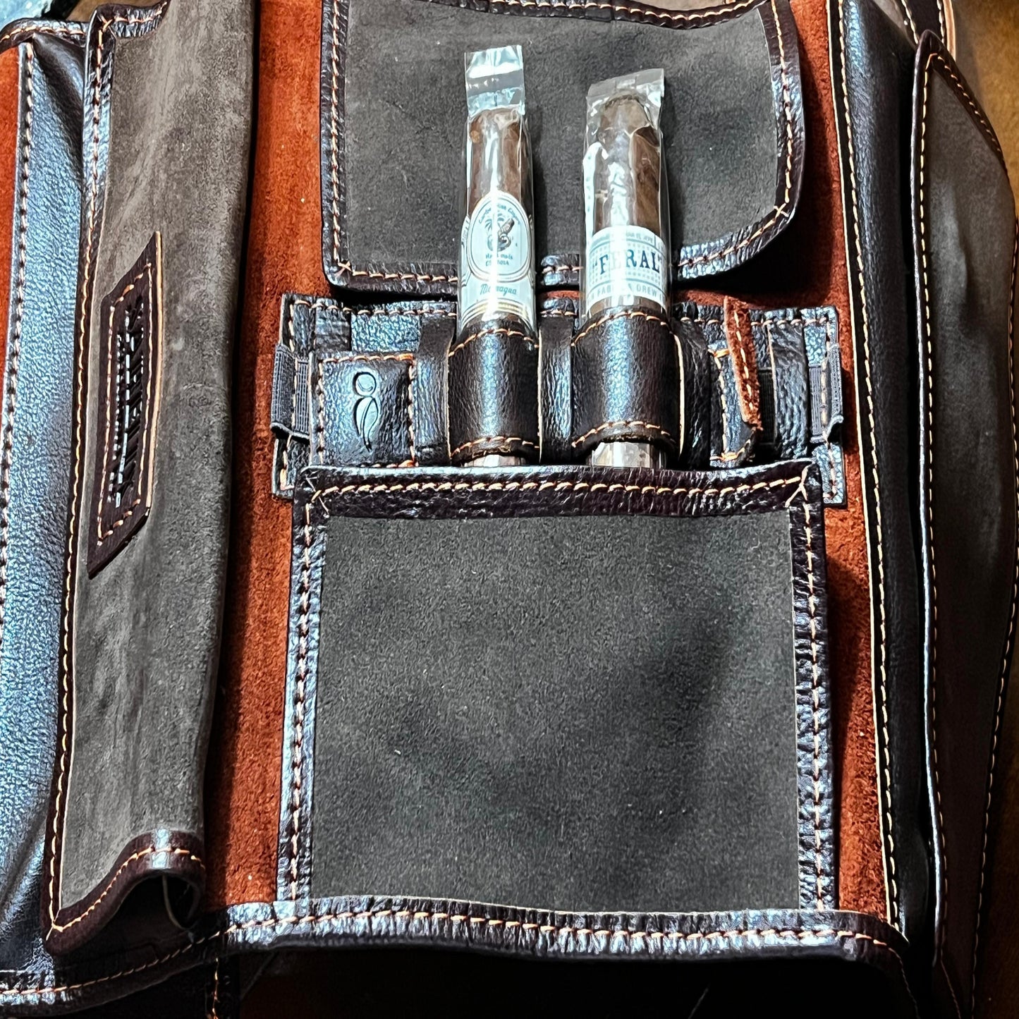 Close-up of a leather bag with two bottles inside, featuring a brand label.