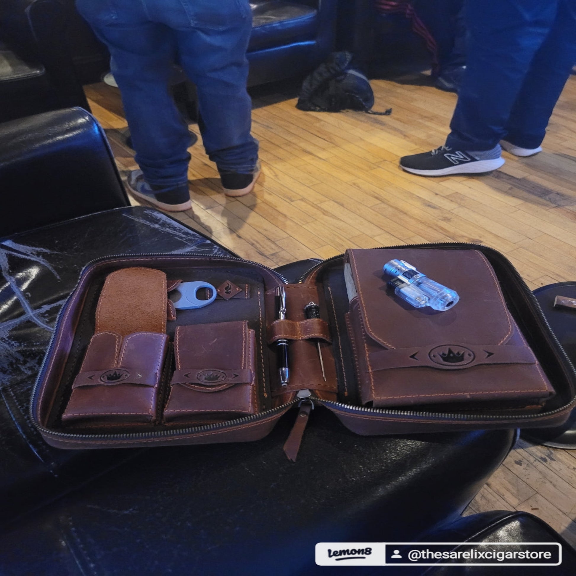 A brown leather luxury cigar humidor with a removable Cedar Cigar Holder and a cigar resting on top.
