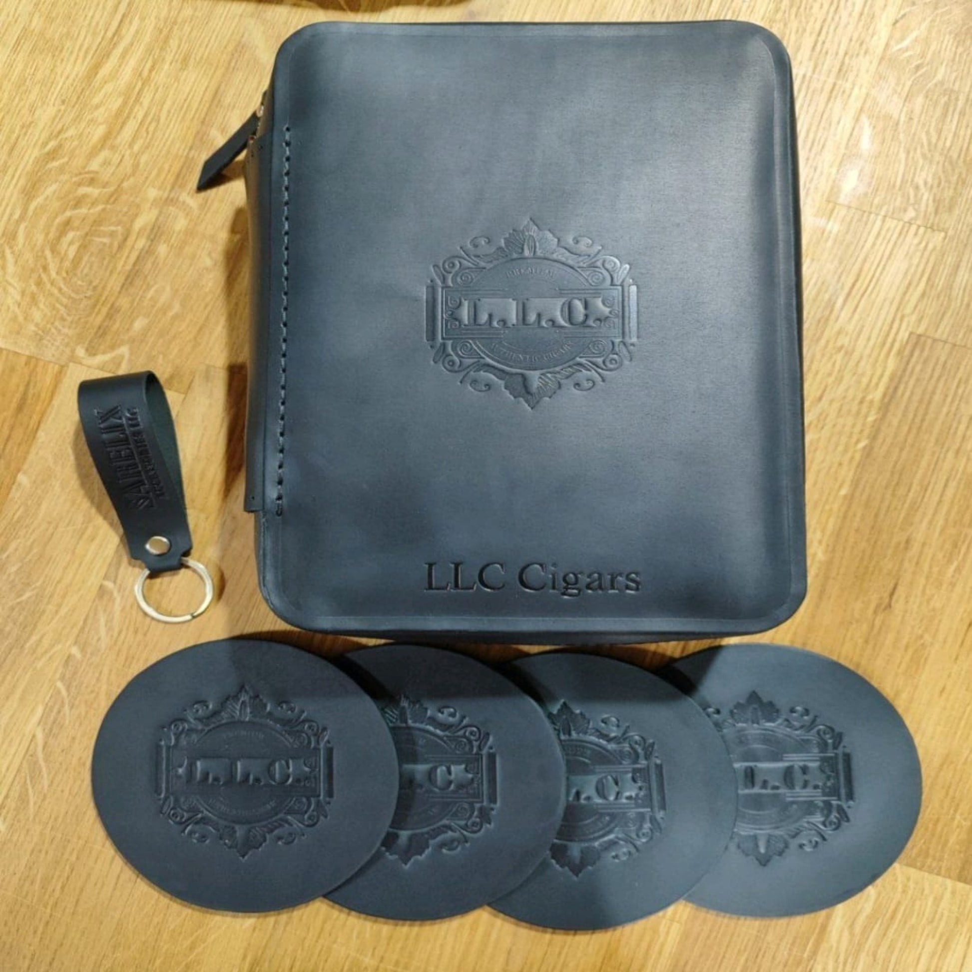 Black leather cigar case with coasters on a wooden surface.