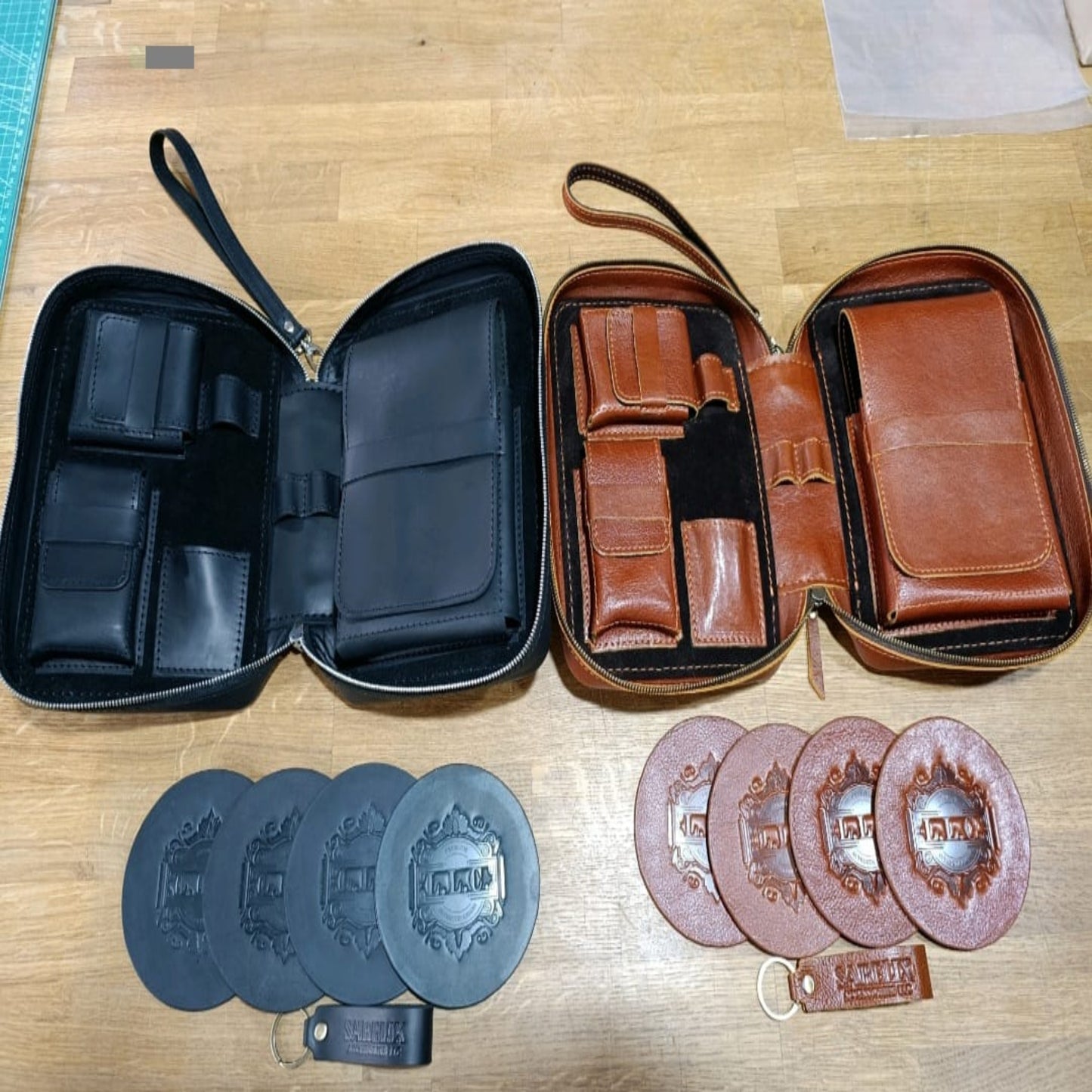 Two open leather cases, one black and one brown, with additional leather items on a wooden surface.